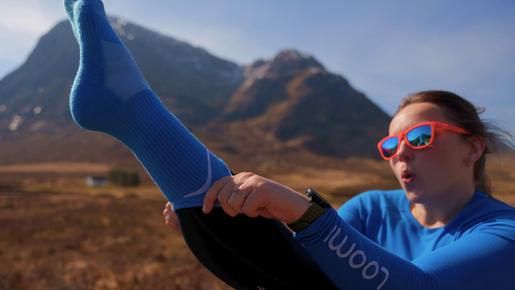 Woman in sunglasses pulling on Loomi Merino Trail Running Socks.