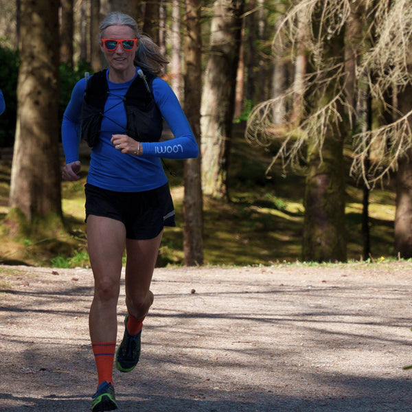 Anne Weir, founder of Loomi Activewear running along a wooded trail. 